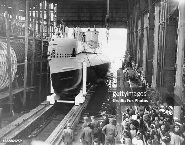Dock workers look on as HMS Sterlet an S-class submarine of the Royal Navy is launched down the slipway on 22nd September 1937 at the Royal Navy...