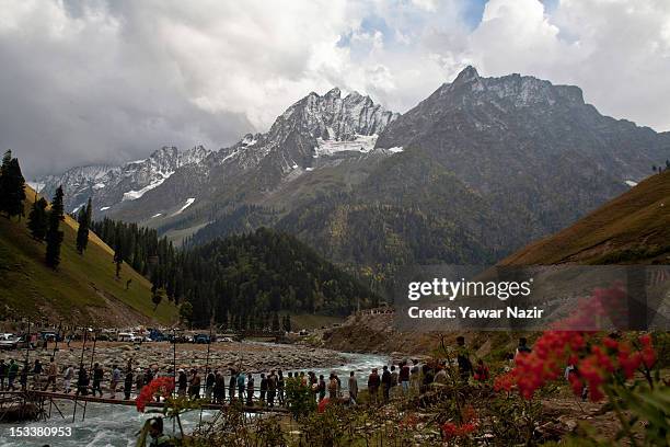 People cross a bridle path next to a glacier to reach the venue where a foundation stone-laying ceremony for a tunnel on the Srinagar-Leh highway was...