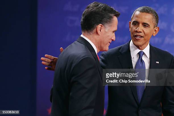 Democratic presidential candidate, U.S. President Barack Obama pats Republican presidential candidate, former Massachusetts Gov. Mitt Romney on the...