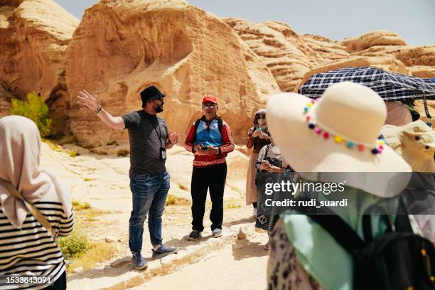 guía turístico explicando la ciudad de petra al grupo turístico asian traveler - the siq fotografías e imágenes de stock