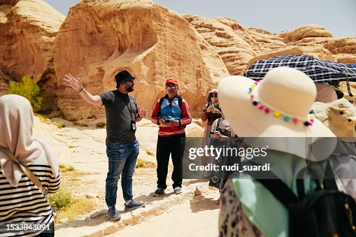 Tour guide explaining Petra city to tour group  Asian Traveler