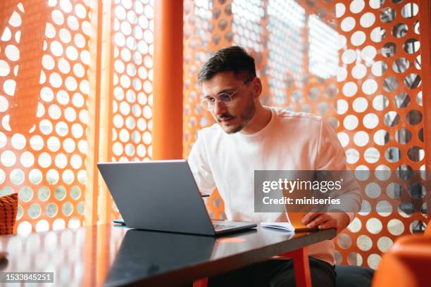 handsome entrepreneur working in the cafe and writing ideas in his notebook - image focus technique stock pictures, royalty-free photos & images