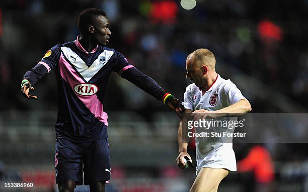 Bordeaux player Ludovic Sane attempts to halt a pitch invaders progress during the UEFA Europa League match between Newcastle United and FC Girondins...