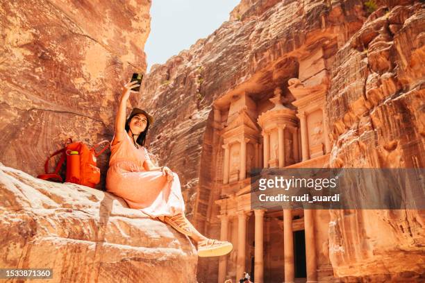 an asian tourist in the hidden city of petra, jordan - sand stone wall stock pictures, royalty-free photos & images