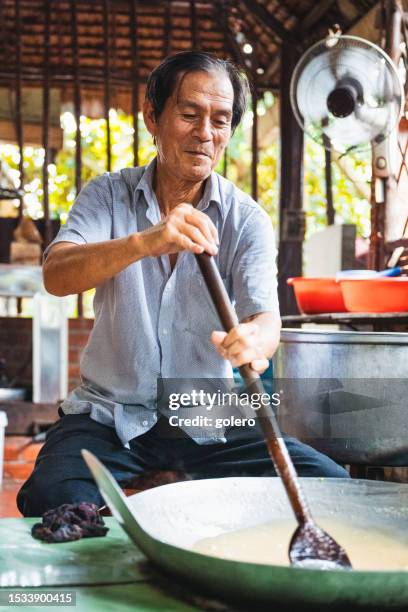 senior man making caramel in huge iron pan in vietnam - vietnamese food stock pictures, royalty-free photos & images