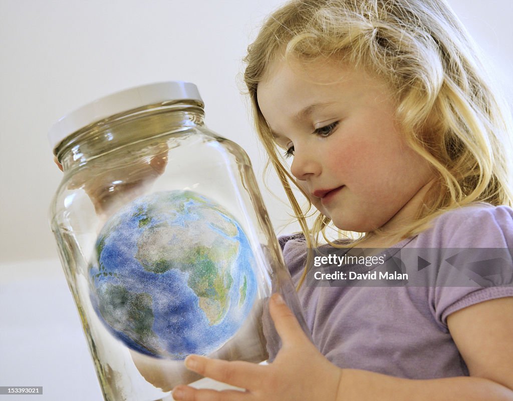 Young girl looking at the world in a jar.