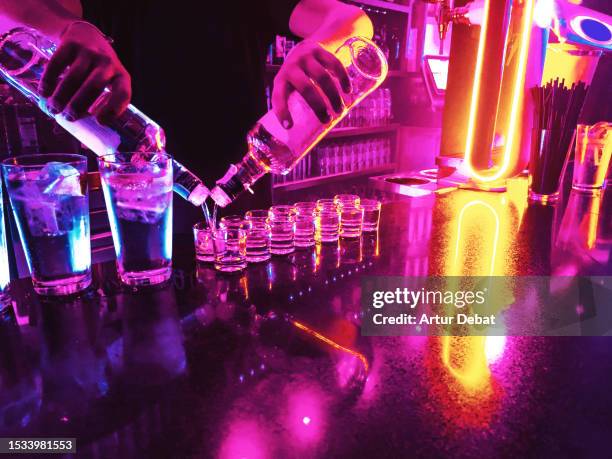 bartender serving alcohol shots in neon illuminated bar. - tequila sterkedrank stockfoto's en -beelden