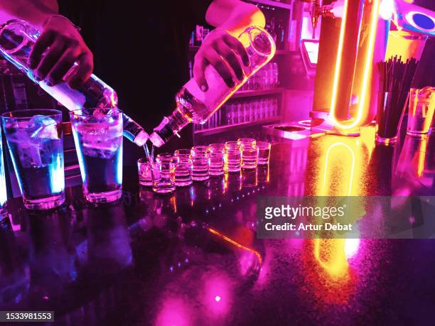 bartender serving alcohol shots in neon illuminated bar. - slak stock pictures, royalty-free photos & images