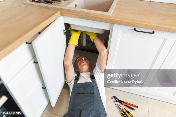 the plumber fixing the sink in the kitchen - water pipe stock pictures, royalty-free photos & images