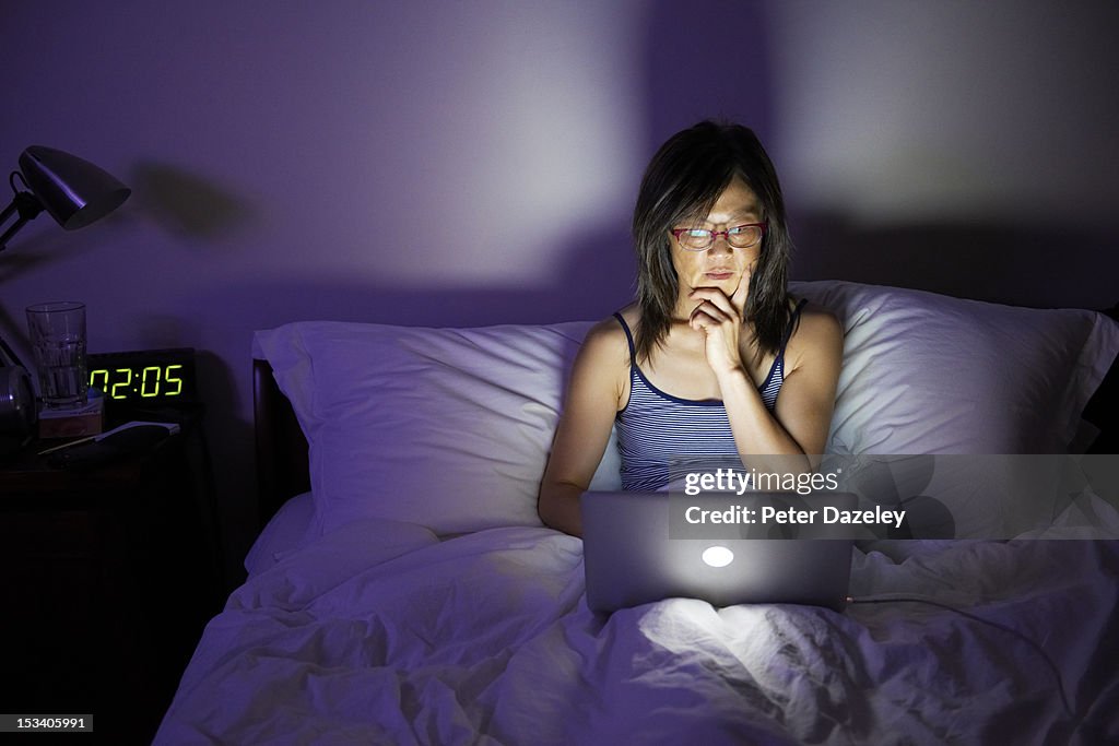 Woman working late on laptop in bed