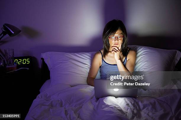 woman working late on laptop in bed - sitting at a laptop with facebook stock pictures, royalty-free photos & images