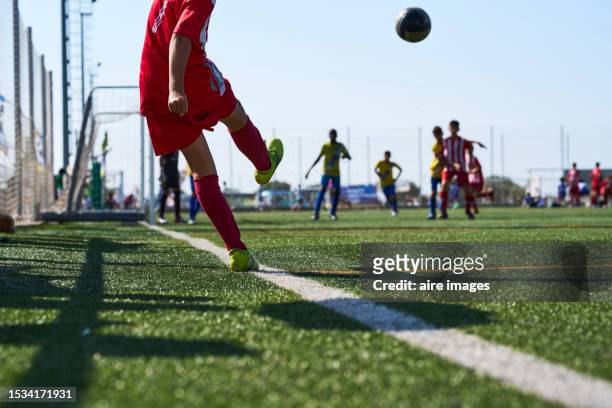 rear view of a boy in sportswear kicking the soccer ball with a corner kick for his team - boy in da corner live stock-fotos und bilder
