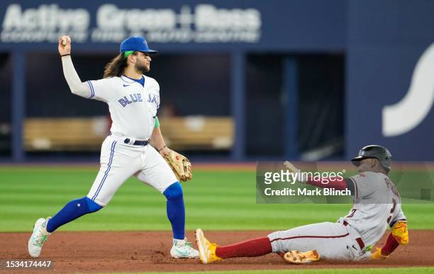 Bo Bichette of the Toronto Blue Jays turns a double play over Geraldo Perdomo of the Arizona Diamondbacks during the fifth inning in their MLB game...