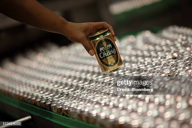 Worker arranges cans of Thai Beverage Pcl Chang beer on a conveyor system as they move along the production line at the company's Beer Thip brewery...