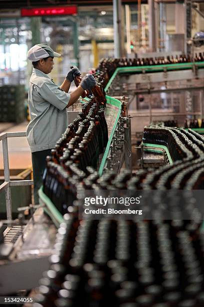 Worker arranges bottles of Thai Beverage Pcl Chang beer on a conveyor system as they move along the production line at the company's Beer Thip...