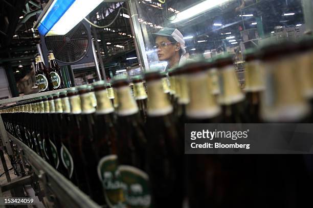 Worker inspects bottles of Thai Beverage Pcl Chang beer as they move along the production line at the company's Beer Thip brewery in Bang Ban,...