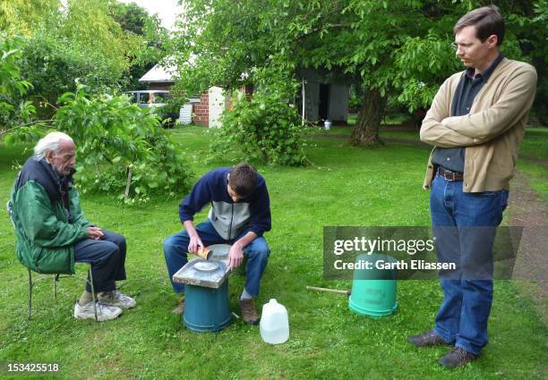 During an outdoor telescope-making workshop, American astronomer John Dobson supervises one of his students during the rough-grinding process to make...