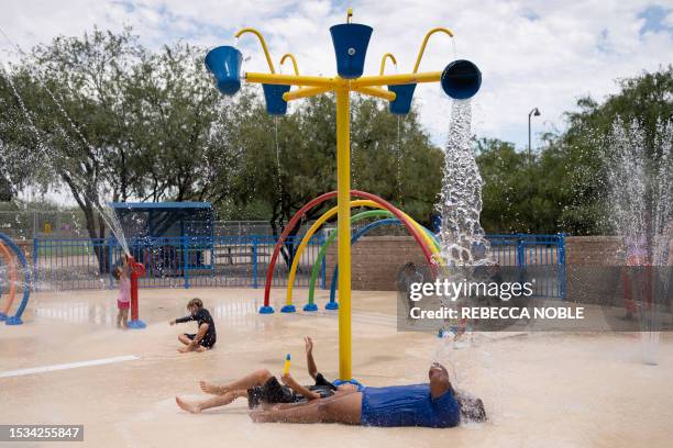 Residents frolic in the splash pad at Brandi Fenton Memorial Park during a heat wave in Tucson, Arizona, on July 15, 2023. Brutally high temperatures...