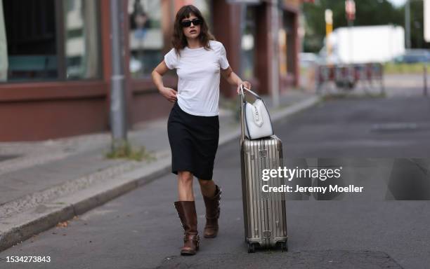 Lea Naumann is seen wearing black sunglasses from Prada, a white tee from Mother Denim, a black knee-length vintage skirt, brown leather boots with...