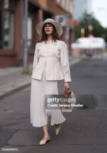 Lea Naumann is seen wearing a natural-colored hat made of palm fibers from Louis Vuitton, a cream-white long-sleeved shirt with white lace details on...