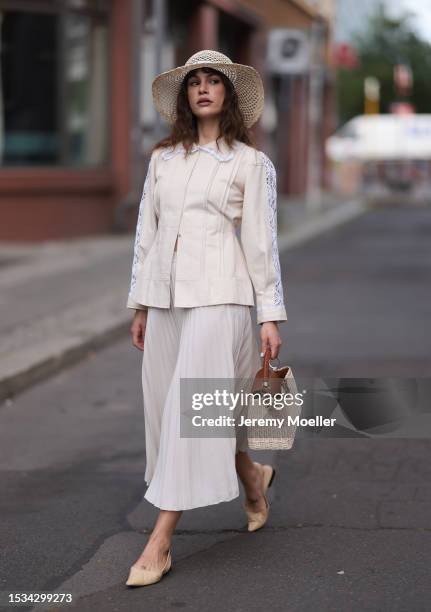 Lea Naumann is seen wearing a natural-colored hat made of palm fibers from Louis Vuitton, a cream-white long-sleeved shirt with white lace details on...