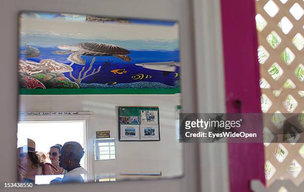 Tourists, peopleand a indigenous women are reflected in a mirror of a bahamian restaurant on June 15, 2012 in Cat Island, The Bahamas.