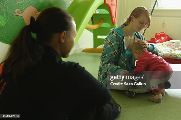 Single mother Nancy Kett and volunteer Anja Goeckeritz play with Kett's 11-month-old daughter Lucy in the playroom of the "Jule" facility for single...