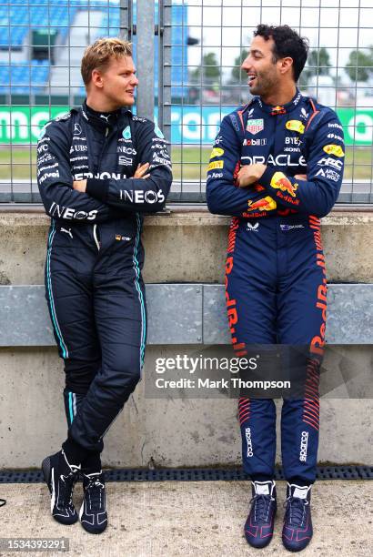 Daniel Ricciardo of Australia and Oracle Red Bull Racing talks with Mick Schumacher of Germany, Reserve Driver of Mercedes in the Pitlane during...