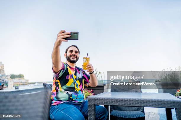 man taking selfie in a seaside bar - online happy hour stock pictures, royalty-free photos & images