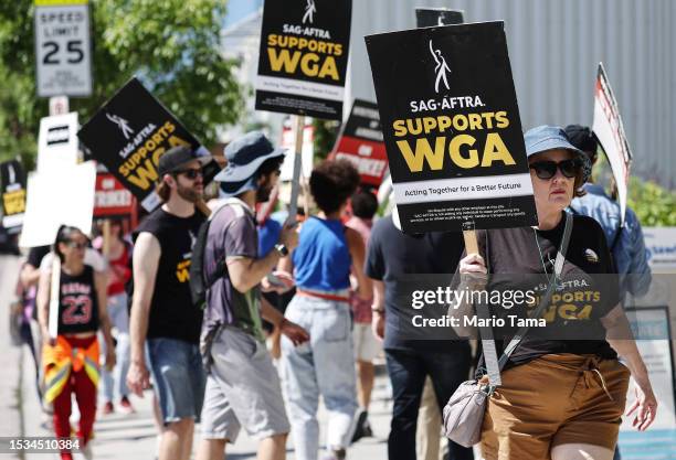 Signs read 'SAG-AFTRA Supports WGA' as SAG-AFTRA members walk the picket line in solidarity with striking WGA workers outside Netflix offices on July...