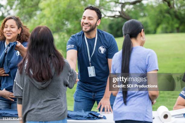 joven adulto se da la mano de la voluntaria - voluntario fotografías e imágenes de stock