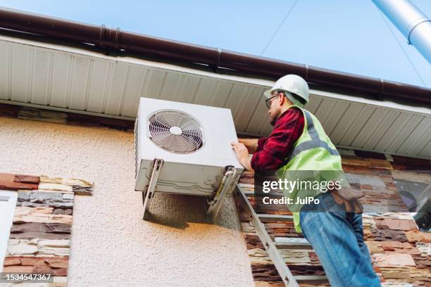 technician in uniform repairing heat pump - air duct repair stock pictures, royalty-free photos & images