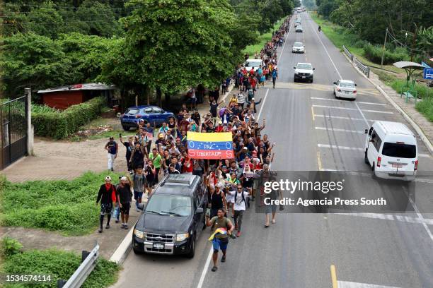 Aerial view of migrants holding flags of Venezuela and walking as part of a migrant caravan heading to the US through Mexico on July 15, 2023 in...
