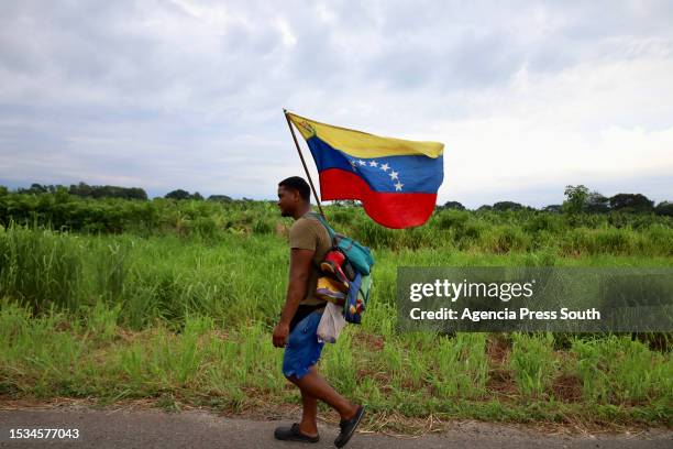 Migrant with a Venezuelan flag walks as part of a migrant caravan heading to the US through Mexico on July 15, 2023 in Ciudad Hidalgo, Mexico....