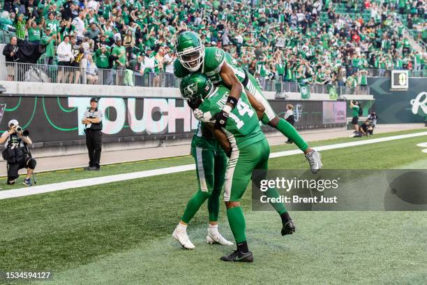 Tevin Jones of the Saskatchewan Roughriders is congratulated by teammates after a touchdown in the game between the Calgary Stampeders and...