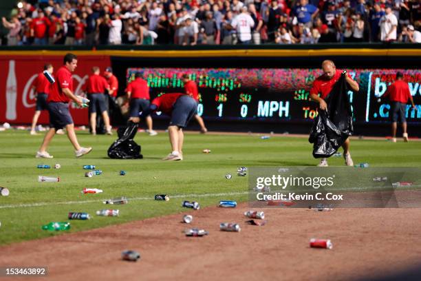 Grounds crew members clean up bottles and cups thrown by fans after the home fans disagree with an infield fly ruling on a ball hit by Andrelton...