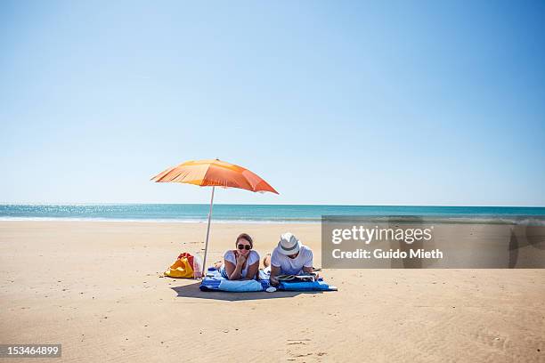 couple under sunshade - beach umbrella sand stock pictures, royalty-free photos & images