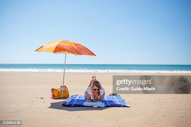 woman with book on beach - parasols stockfoto's en -beelden