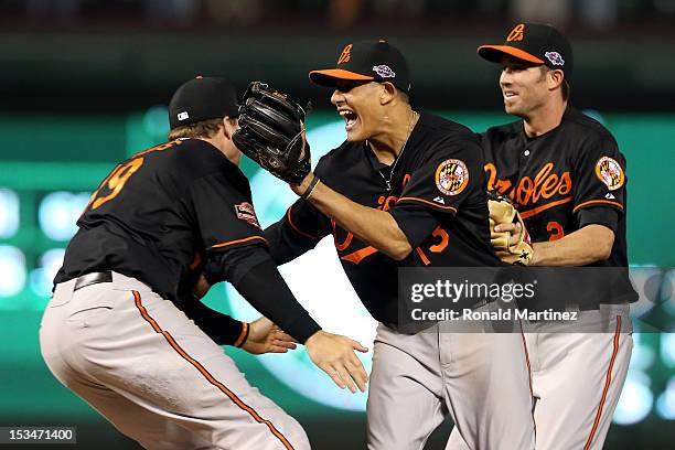 Chris Davis, Manny Machado and J.J. Hardy of the Baltimore Orioles celebrate after they won 5-1 against the Texas Rangers during the American League...