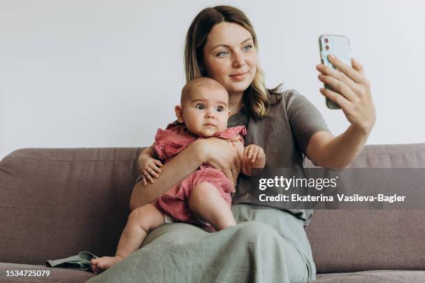 beautiful mom and baby talk with family via video chat - mother daughter webcam - fotografias e filmes do acervo