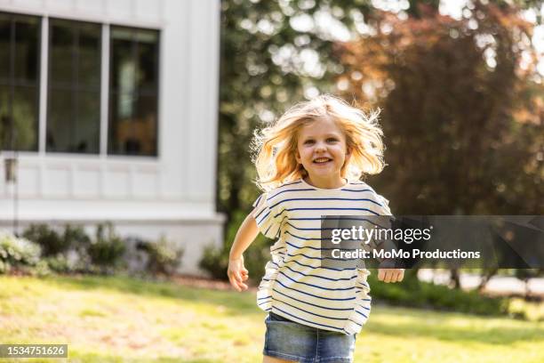 young girl running in front of suburban home - girls laughing stock pictures, royalty-free photos & images