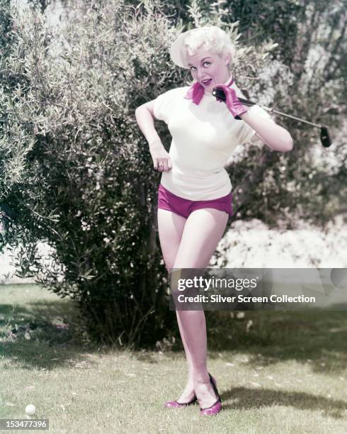 American actress Sheree North playing golf in pink shorts, circa 1955.