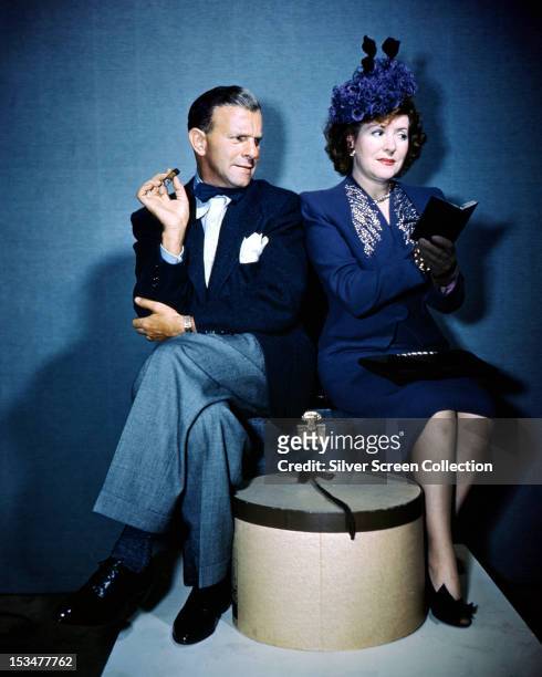 American comedians George Burns and his wife Gracie Allen , circa 1940. The couple are sitting on a suitcase, with Burns smoking a cigar and Allen...