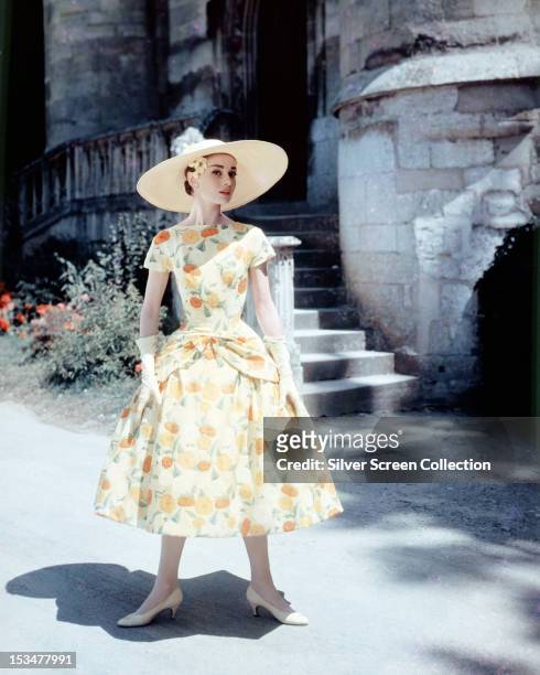 Belgian-born actress Audrey Hepburn in a floral-print day dress and sun hat, circa 1955.