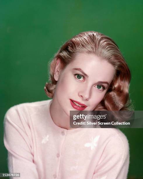American actress Grace Kelly wearing a pink cardigan, circa 1955.
