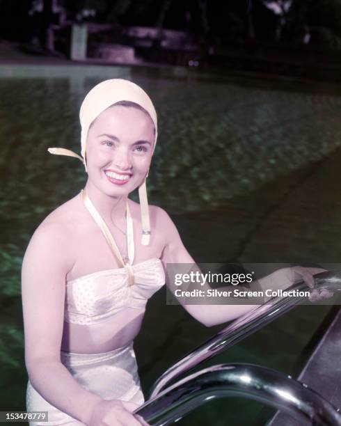 American actress and singer Ann Blyth emerging from a swimming pool in a bikini and swimming cap, circa 1950.