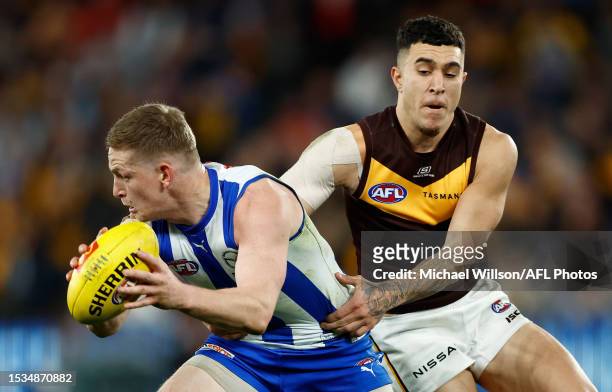 Jack Ziebell of the Kangaroos is tackled by Tyler Brockman of the Hawks during the 2023 AFL Round 18 match between the North Melbourne Kangaroos and...