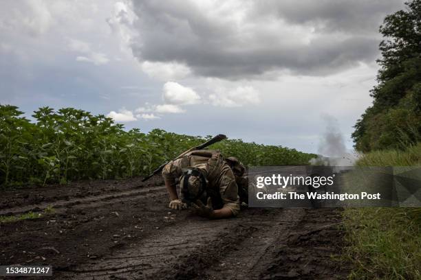 Soldier takes cover as he removes an anti tank mine by tying a rope around the detonator during a mine clearance exercise on July 11 2023, in...