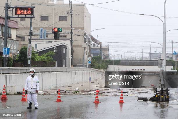 An official stands guard to stop traffic at the entrance to an underpass which flooded due to heavy rains across northern Japan, in the city of...