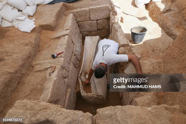 Palestinian archaeologist works on a lead sarcophagus on July 16 the second to be unearthed at a Roman-era necropolis discovered in Gaza city in...